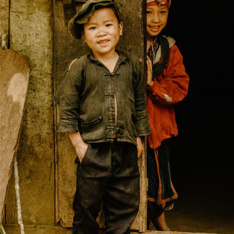 Two children smiling in a wooden doorway