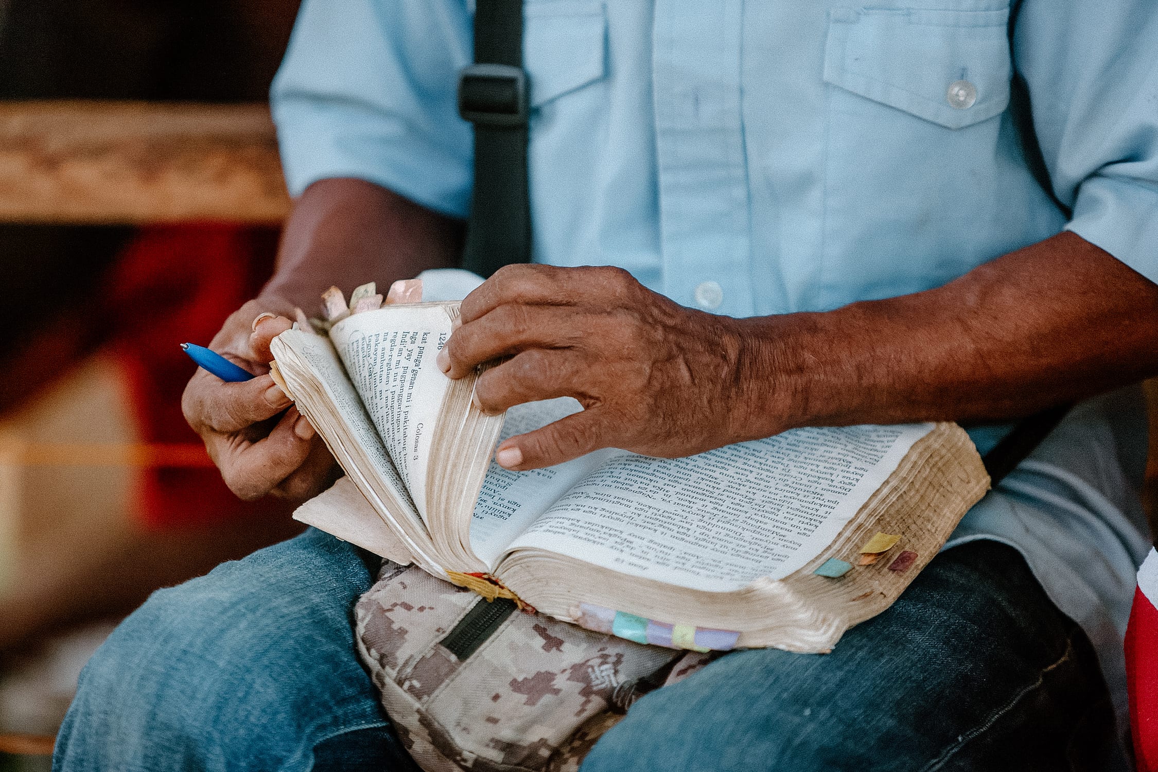 Weathered hands turning the pages of a well-used Bible
